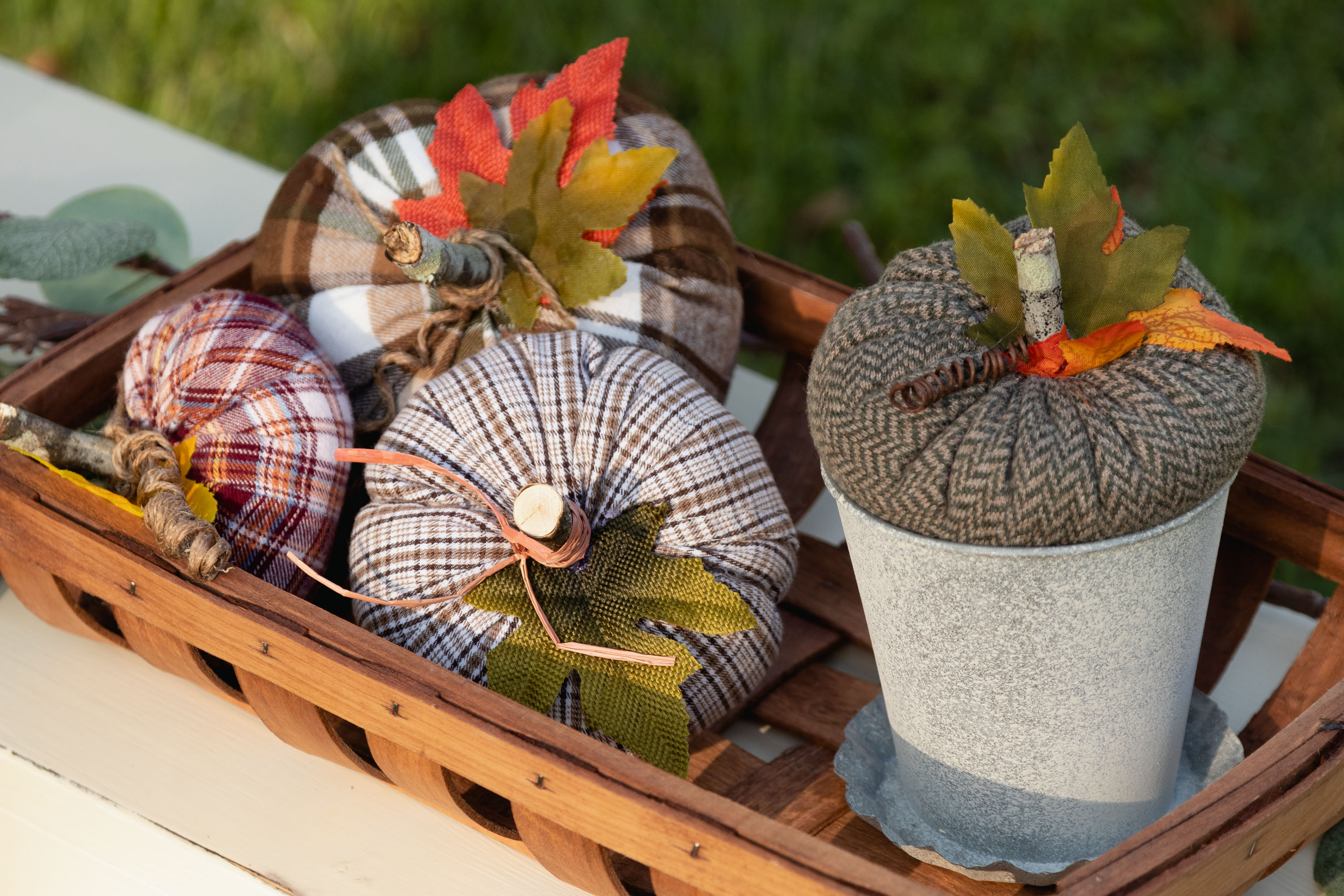 Handmade Plaid pumpkins sitting in a tobacco basket on a bench