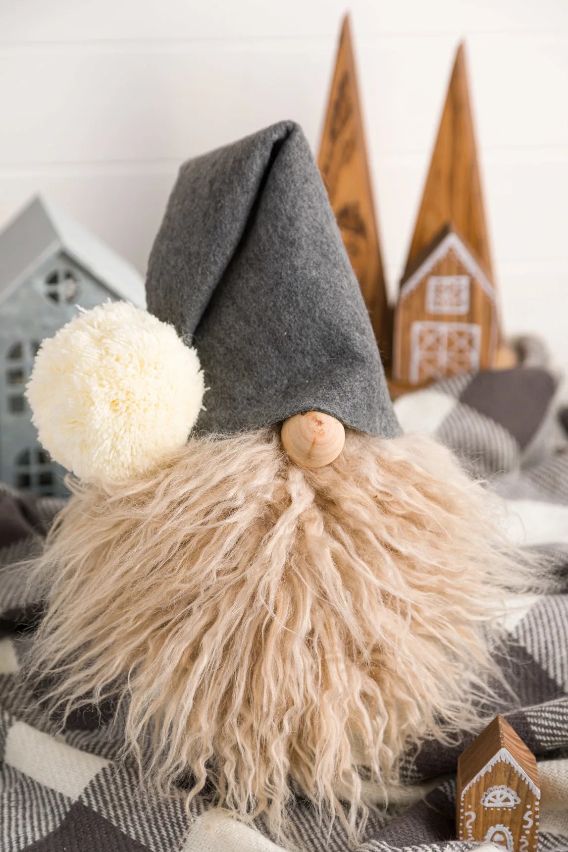 DIY Gnome with a faux fur beard and gray felt hat. Sitting on a gray and while buffalo check throw blanket.