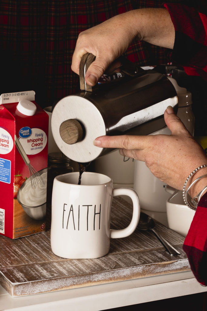 Lady pouring coffee in a mug with the word Faith on it