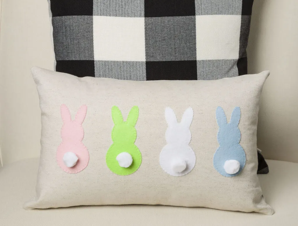 Bunny Pillow Applique with four felt bunny with pom pom tails sitting on a chair