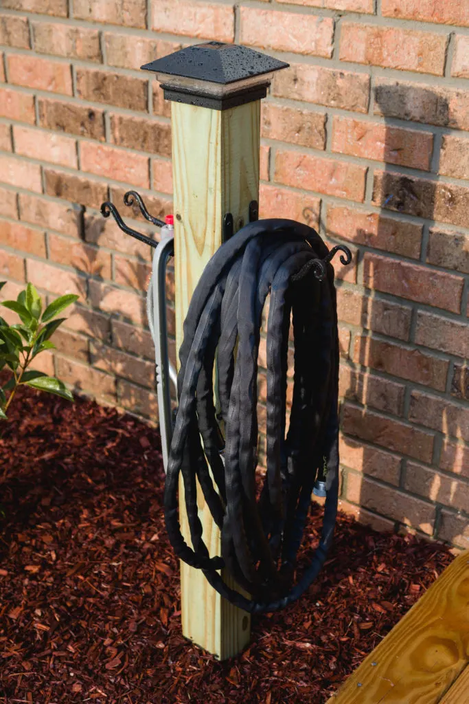 Closeup of completed garden hose storage post with solar light 