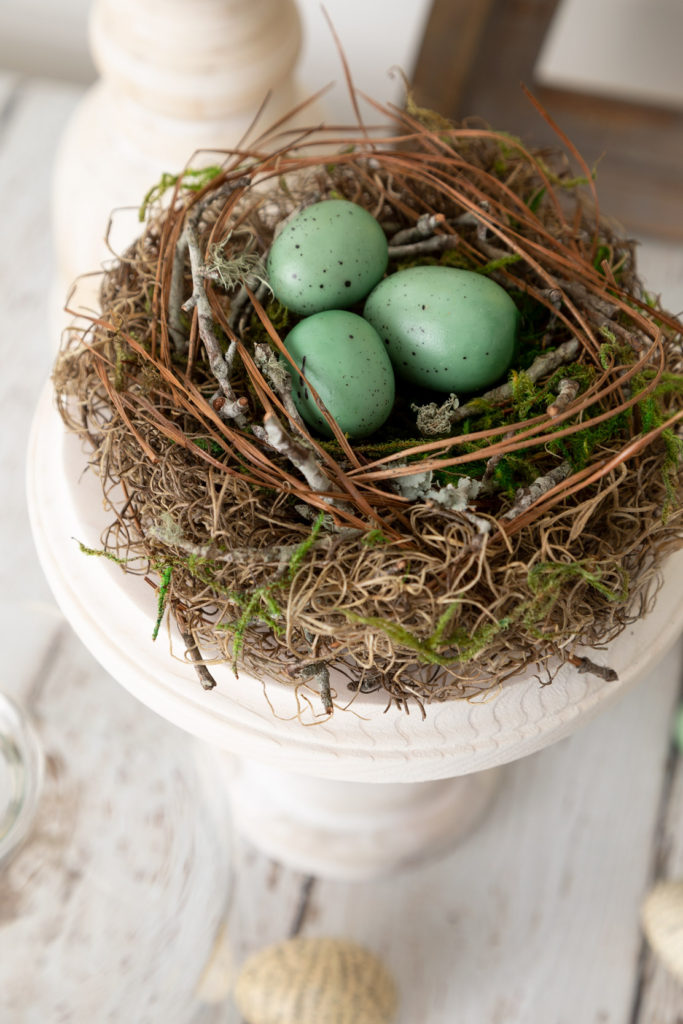 DIY Spring Decor bird nest on pedestal on a wood table