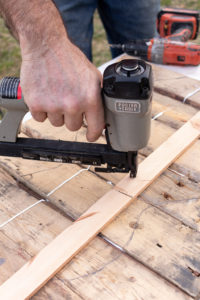 Stapling the battens on the pallet wood pieces on a work table