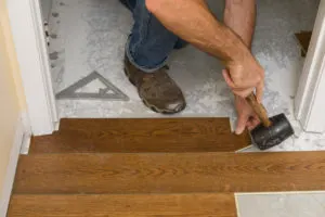 Using a rubber mallet to install flooring under the door jamb