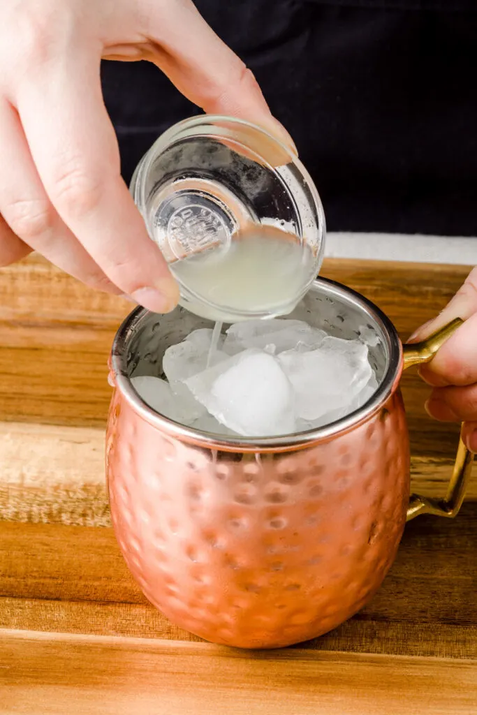 After you fill the mug with ice, add lime juice to mule mugs.