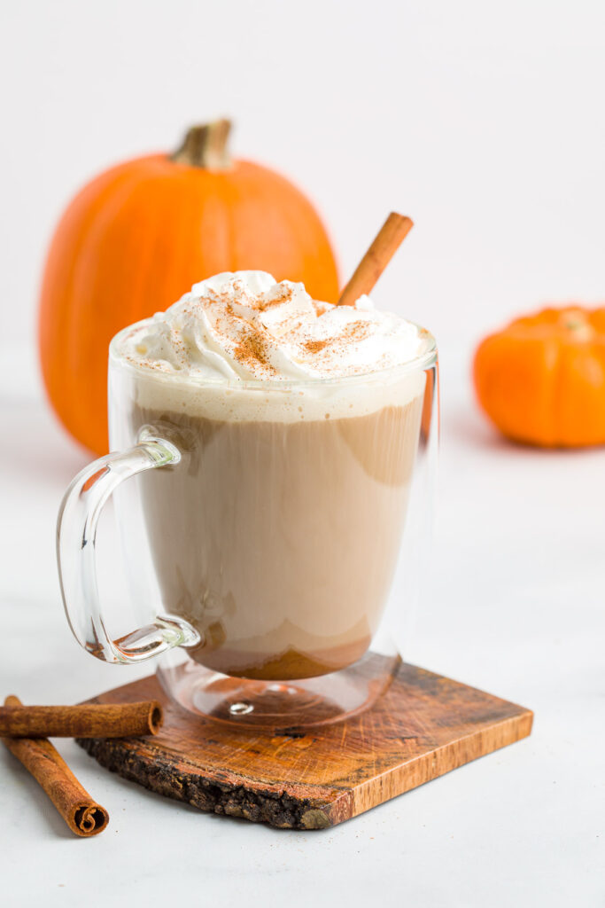 Pumpkin Spice Latte in a clear glass mug with whipped cream and a cinnamon stick