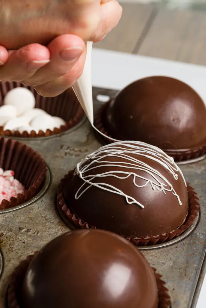 Piping candy over hot chocolate bombs 