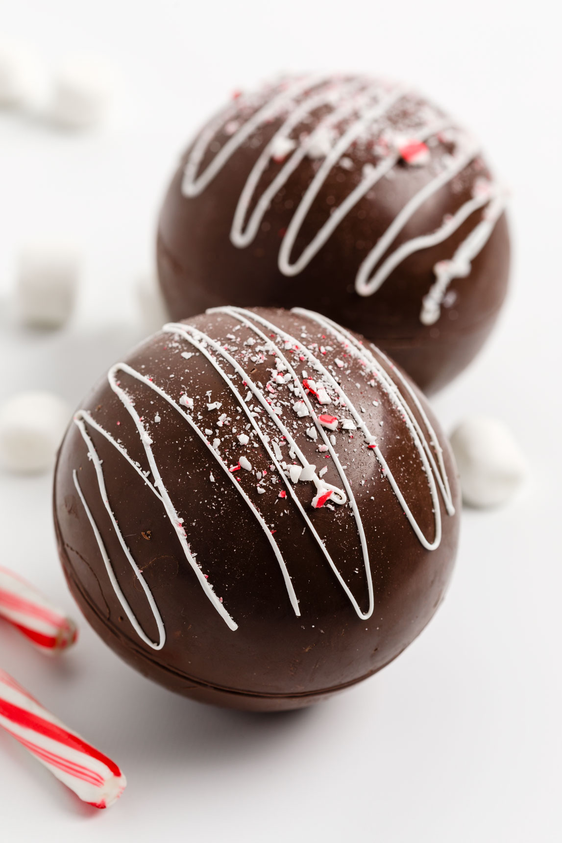 Luxury hot cocoa bombs with white chocolate drizzle over and sprinkled with crushed peppermint