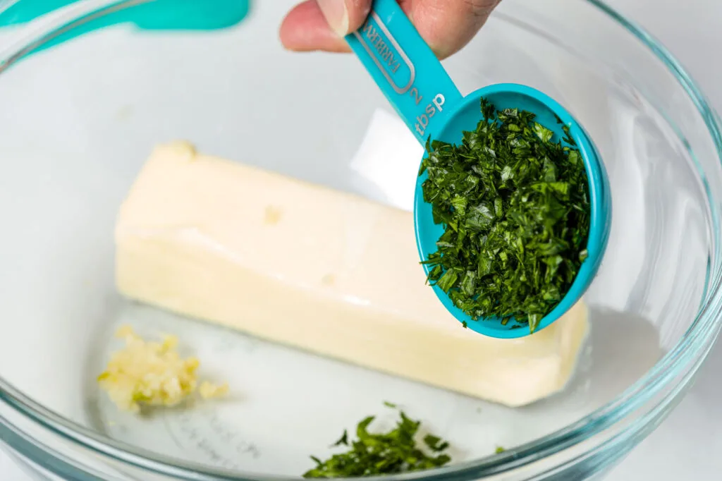 Adding fresh chopped parsley to butter and garlic