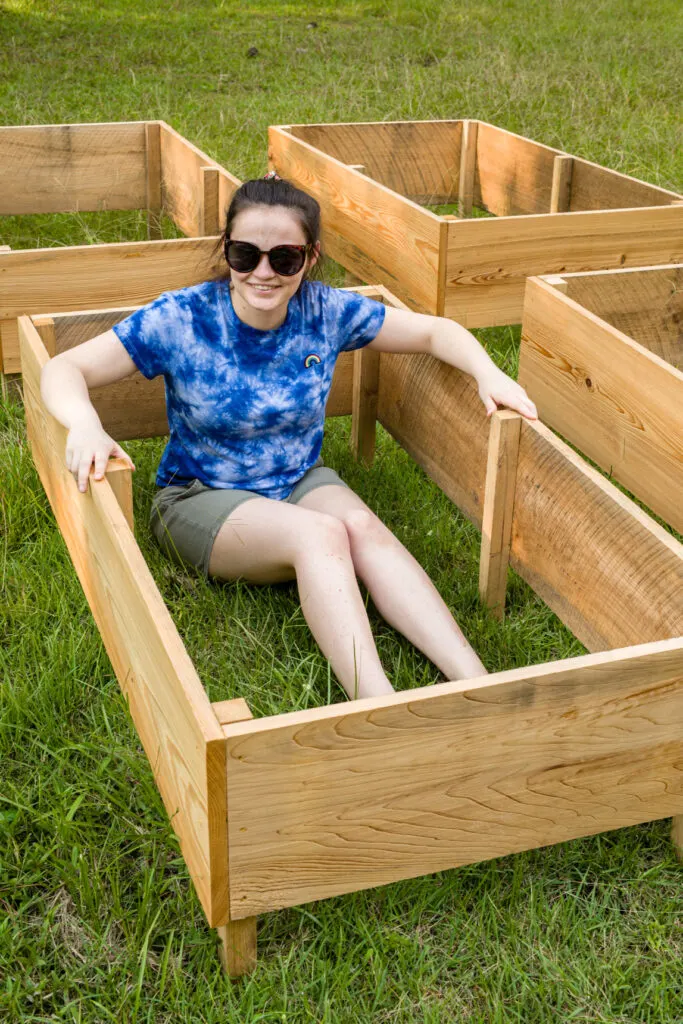 Girl sitting inside DIY wooden garden box on the grass