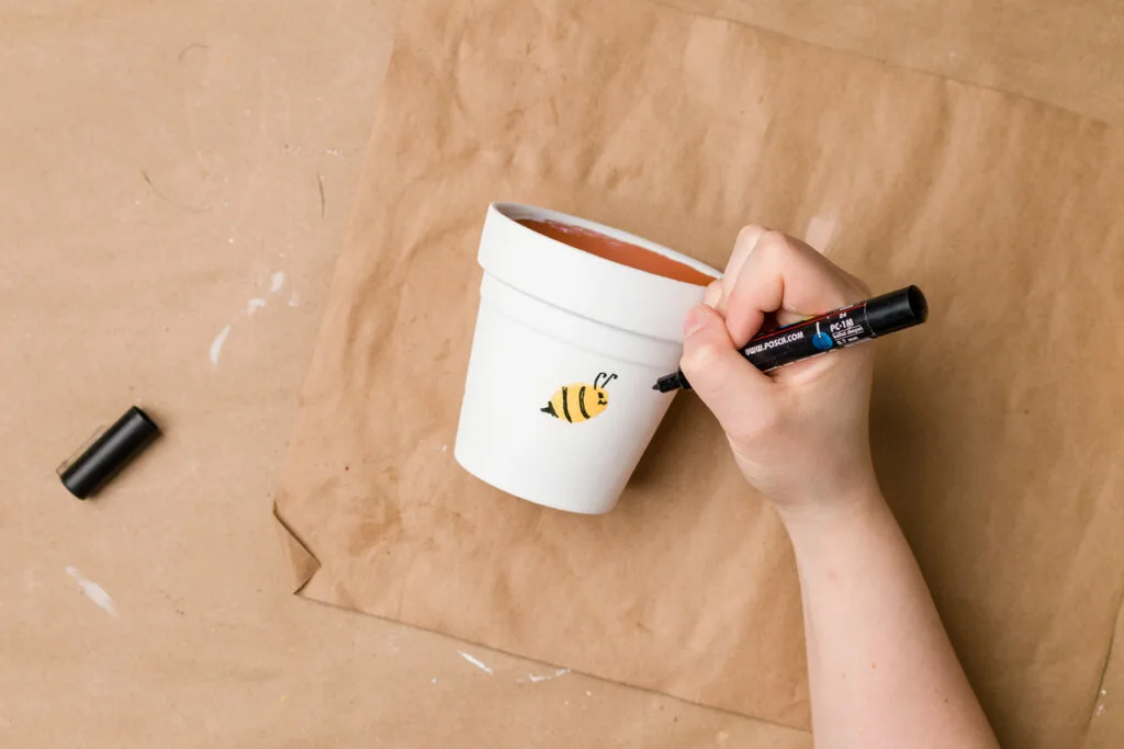 Drawing the antennae and tail on the thumbprint bee flower pot