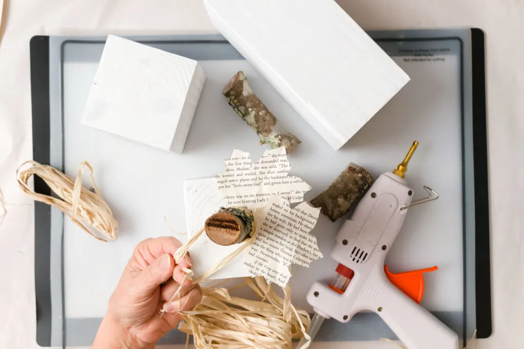 Adding a raffia bow to the white 4x4 wooden pumpkin 