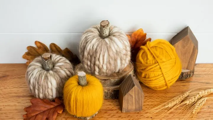 Yarn wrapped Pool noodle pumpkins sitting on a wood table