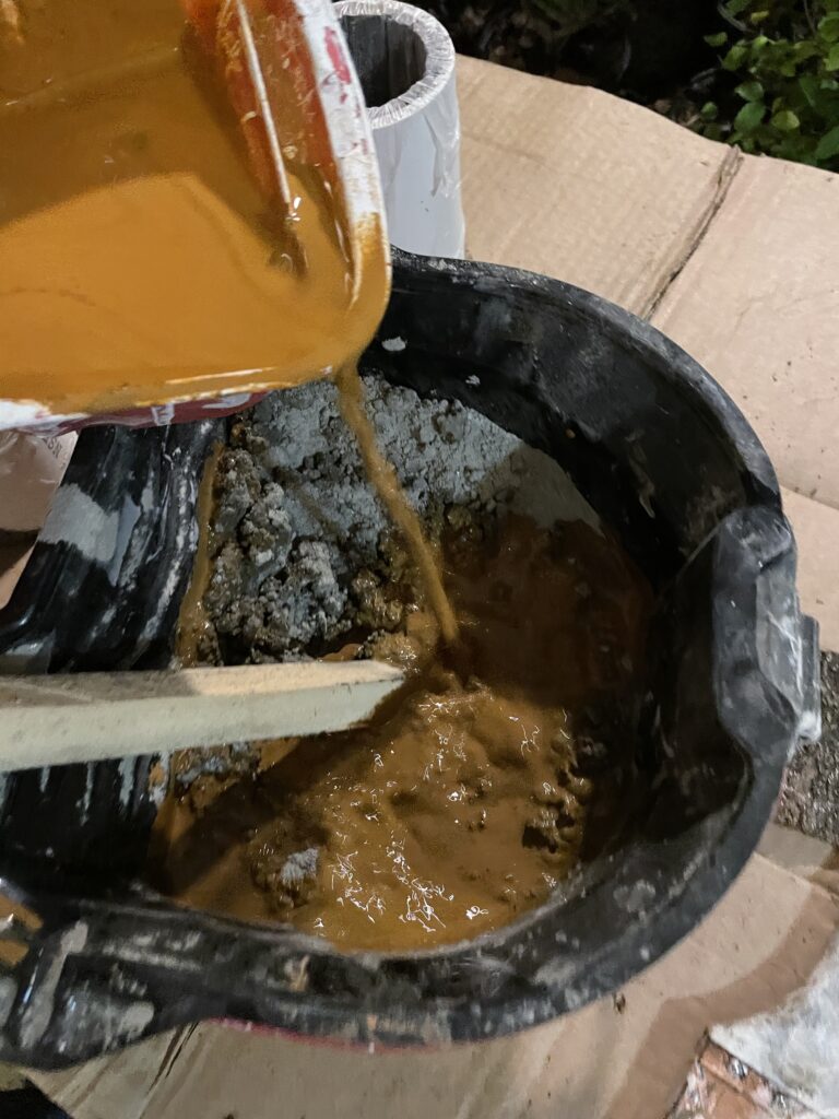Mixing the cement with the liquid color and water in a pail