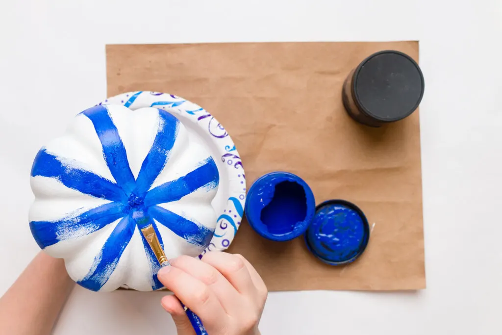 Painting the bottom of the pumpkin with cobalt blue paint