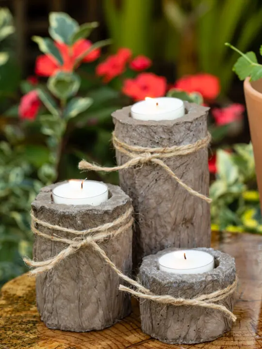 Cement candle holders with twine ties sitting on a wood slice table