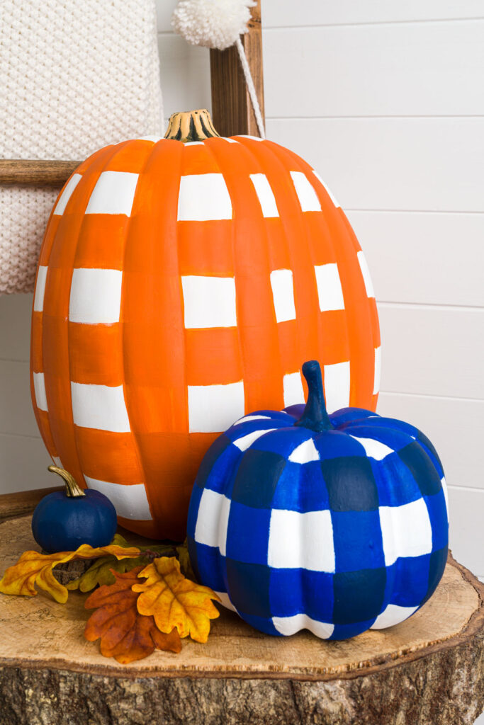 Two pumpkins hand painted with a buffalo plaid pattern 