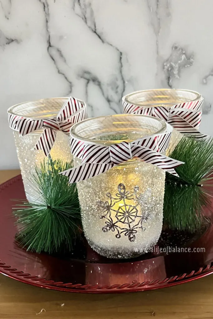 DIY Jar Luminaries with snow and ribbons sitting on a plate 