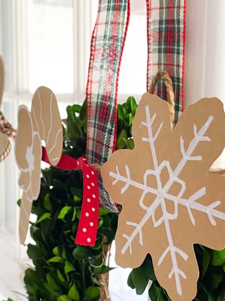 Paper Gingerbread garland decorated with paint markers and Christmas ribbons. Hung over the windows. 