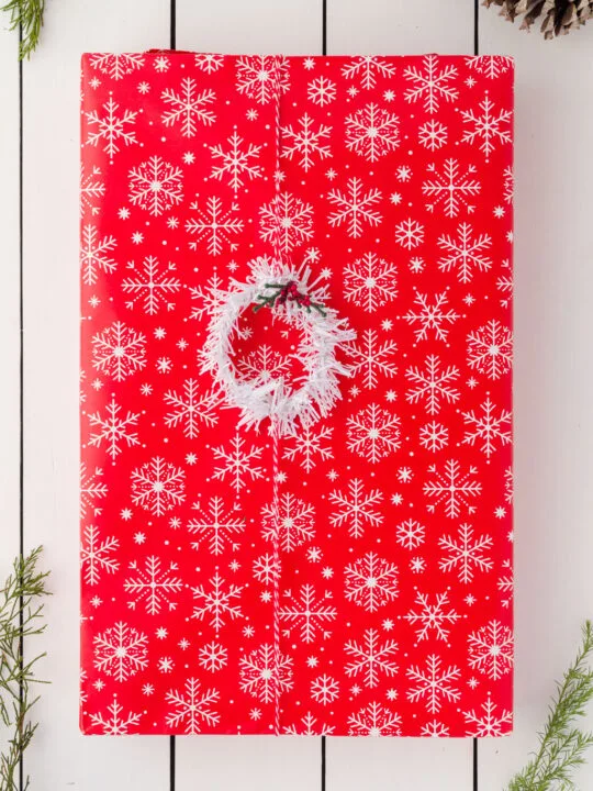 Gift wrapped in red and white paper with a white wreath on it