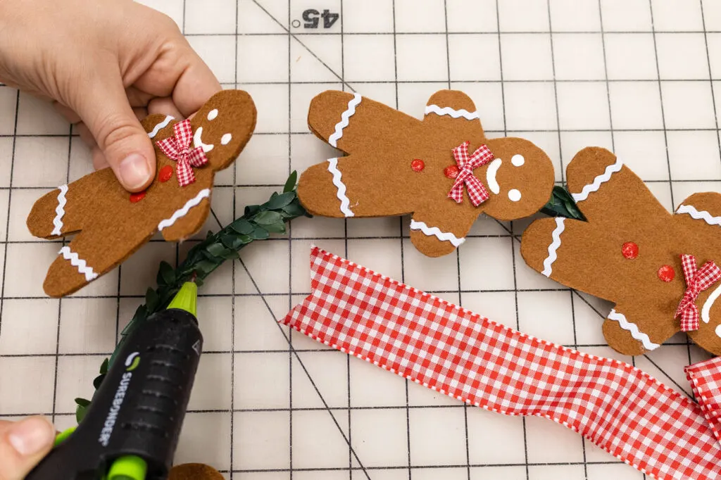 Attaching the gingerbread man to the wreath form with hot glue