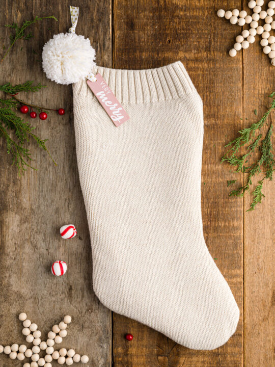 DIY sweater stocking with a pom pom and tag on a wood table