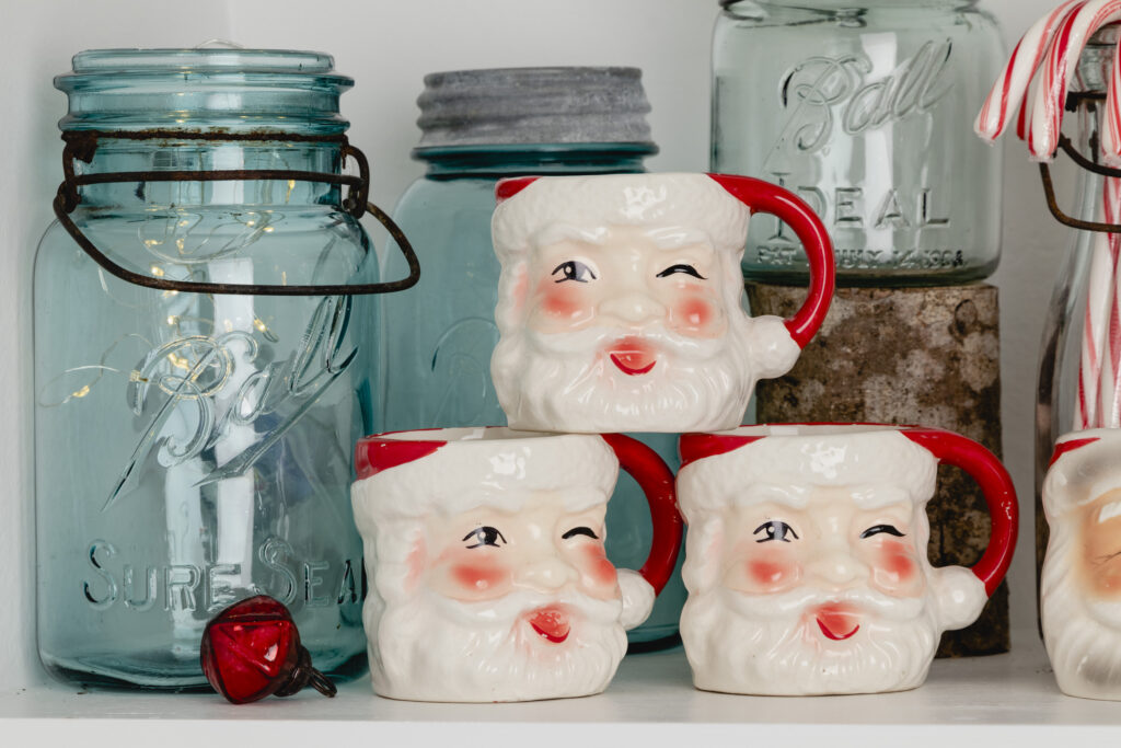 Antique jars and vintage Santa mugs on a shelf with candy canes