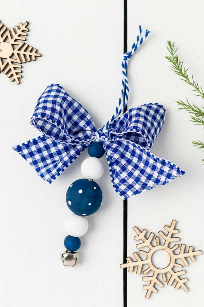 Blue and white wooden bead ornament with a blue and white check bow on a table 