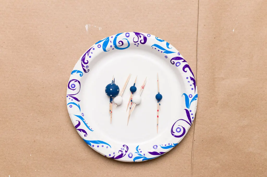Dry wood beads on a paper plate with toothpicks in them
