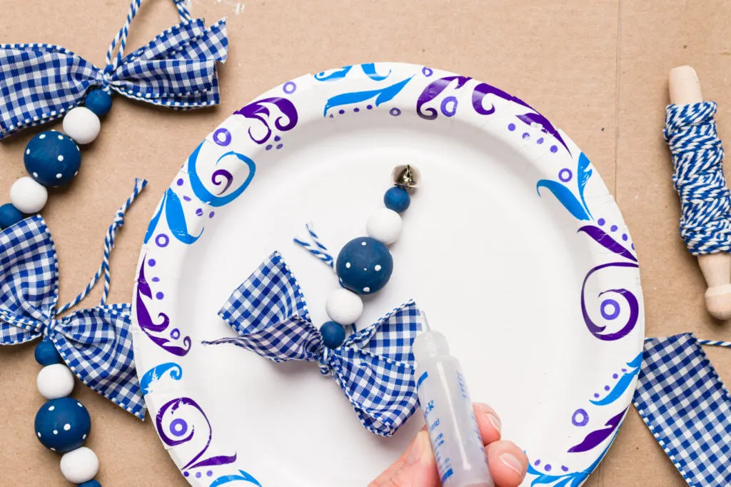 Add fray check to the cut ends of the ribbon bow on a paper plate