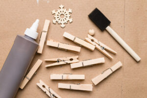 Clothespin snowflake crafting supplies (clothespins, wood stain, wood bead, foam brush) 