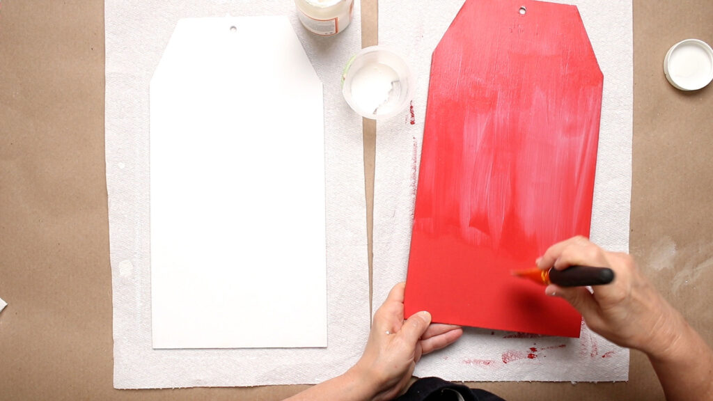 Painting the red piece of the door hanger with Mod Podge 