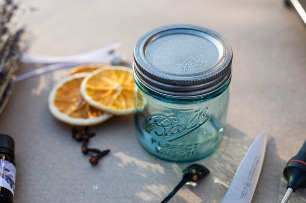 Jar for homemade candle and dried oranges slices for garnish on a table outside