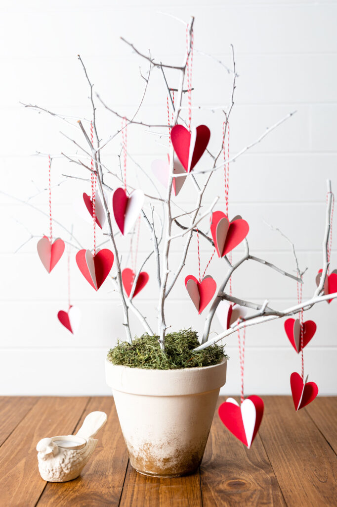 DIY red and white paper hearts hanging from branches in a clay pot 
