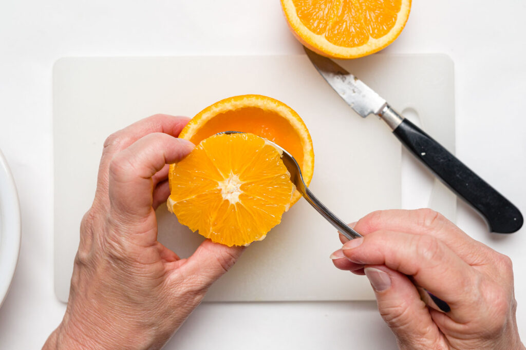 Using a grapefruit spoon to scoop out the orange pulp
