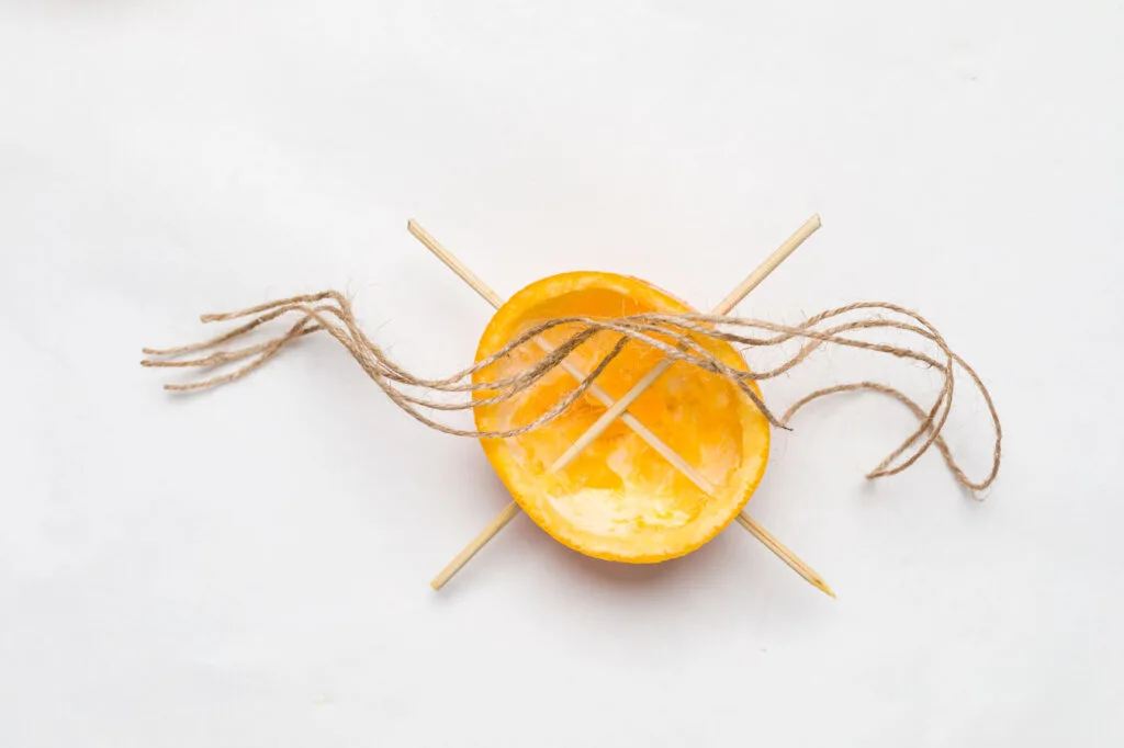 Half of an Orange peel with two skewers inserted with two pieces of twine
