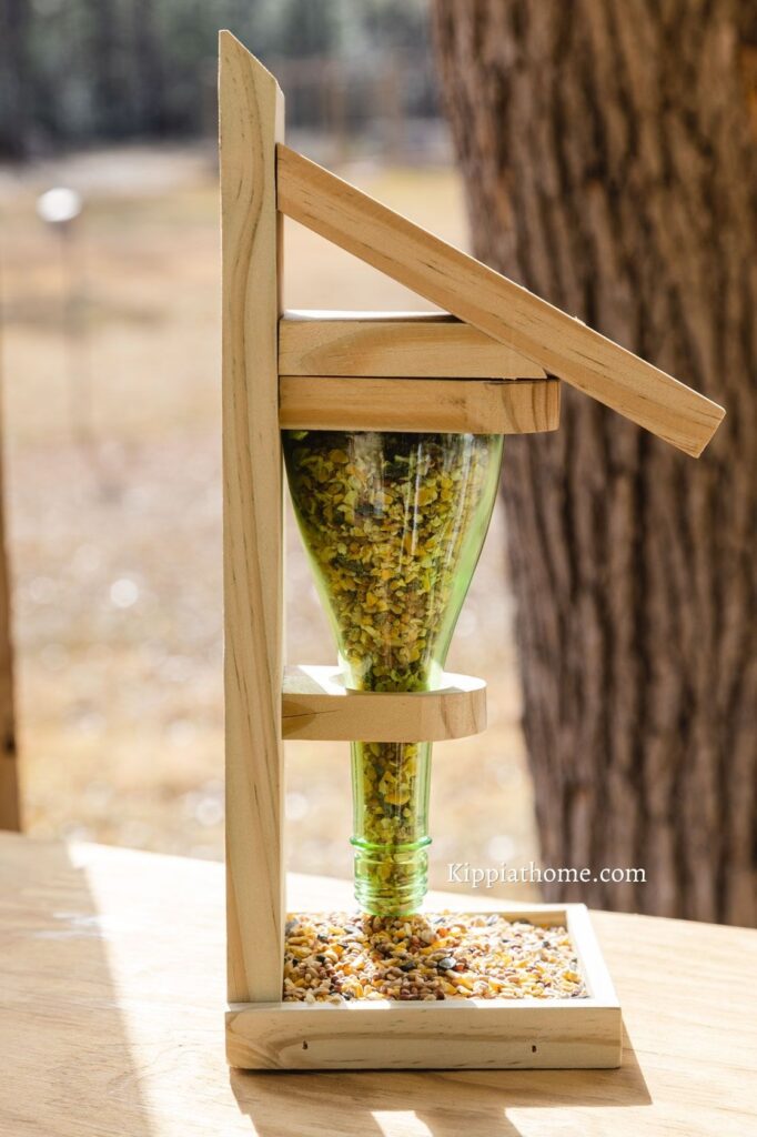 Green wine bottle and wood DIY bird feed on a wood work table outside