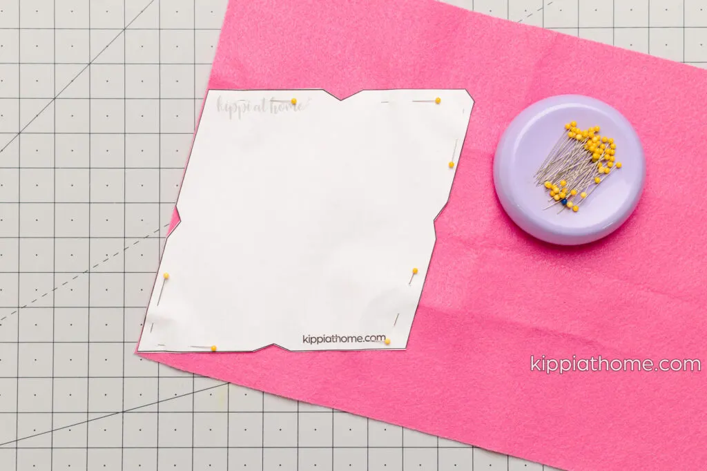 Pink felt with a paper envelope pattern pinned to the it 
