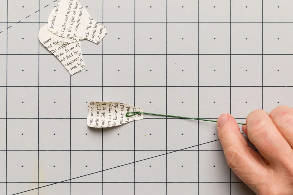 Gluing the floral wire loop to the rolled book page center petal