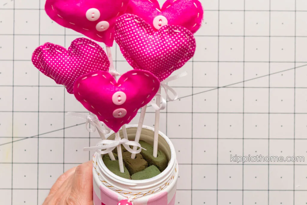Jar filled with pieces of floral foam and the heart with skewers inserted into the floral foam