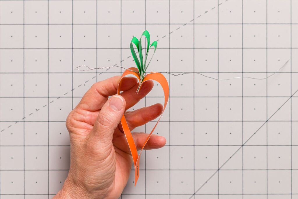 Pushing a wire loop through the holes in the green looped paper