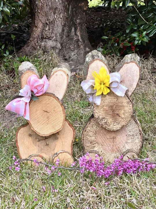 Wood Slice Bunnies with ribbon bows and flowers in the yard