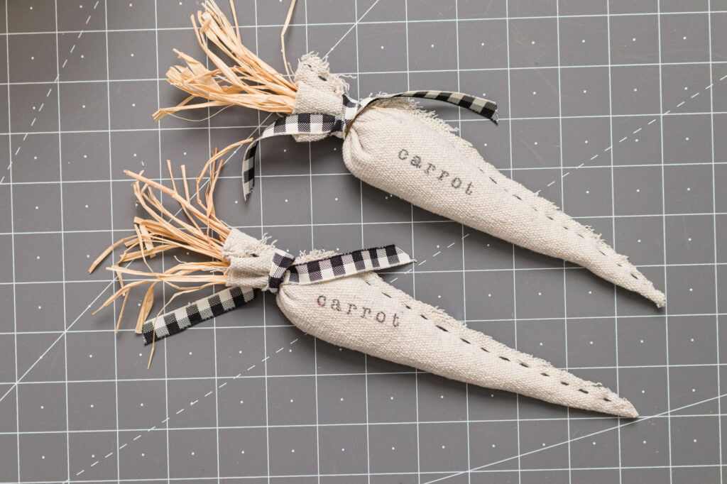 two DIY Easter carrots sitting on a cutting mat