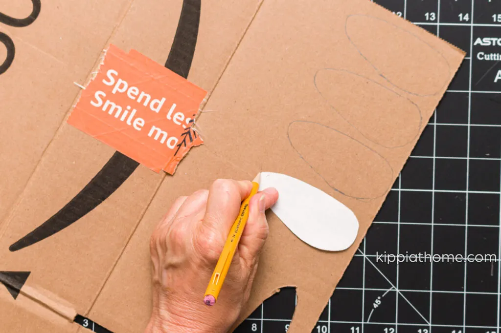 Using a pencil to trace around the paper printout on cardboard