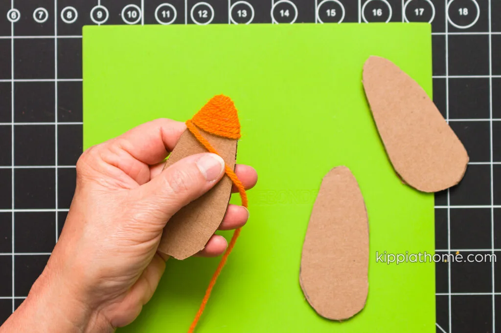 Wrapping yarn around the cardboard cutout on a silicone mat