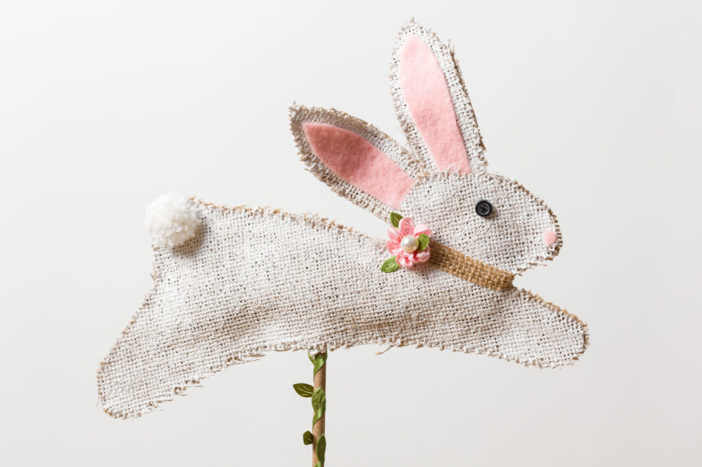 Burlap bunny painted white with a pom pom tail and on a dowel 