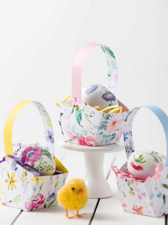 Three Easter Baskets with Easter grass and a decoupage egg on a table