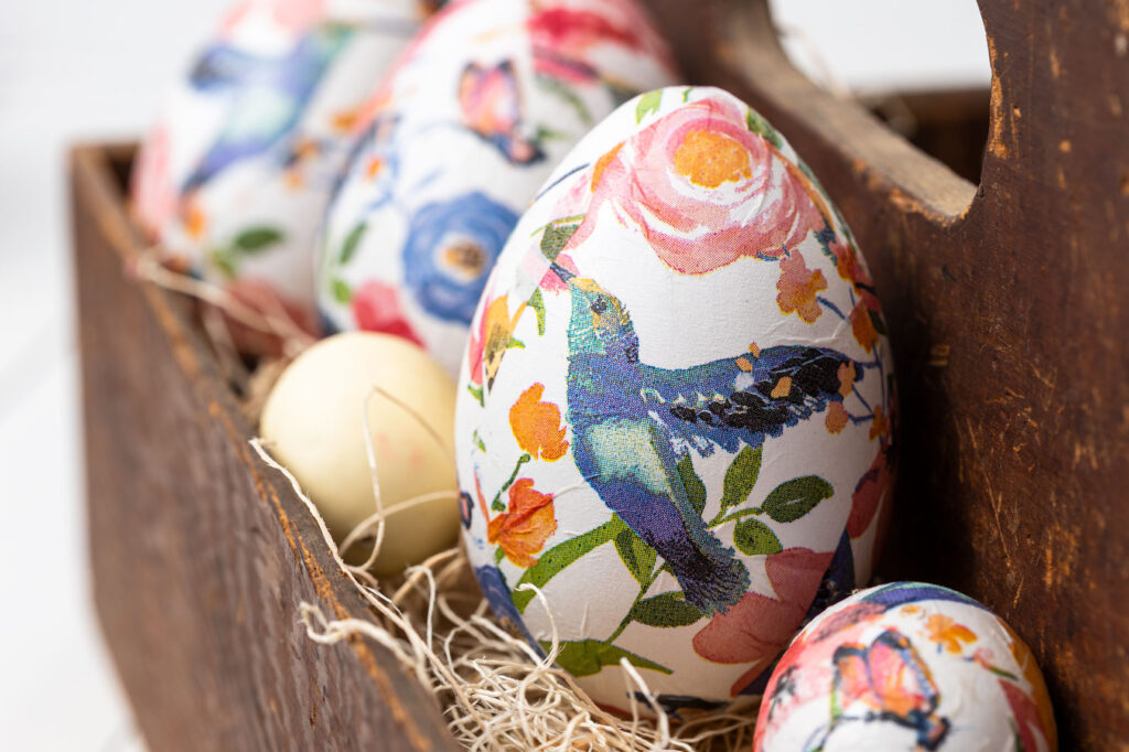 Decoupage eggs in a wooden tool caddy with shredded wood