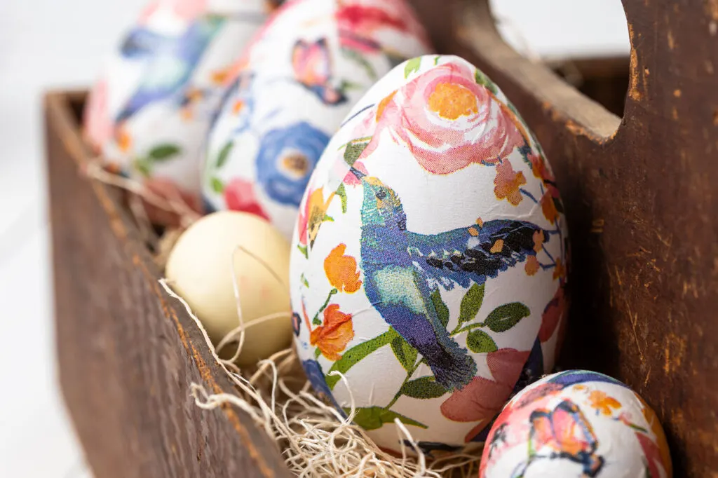 Decoupage eggs in a wooden tool caddy with shredded wood