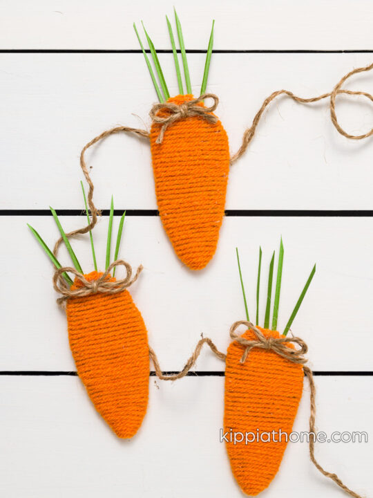 Three DIY yarn carrots on a white table with twine